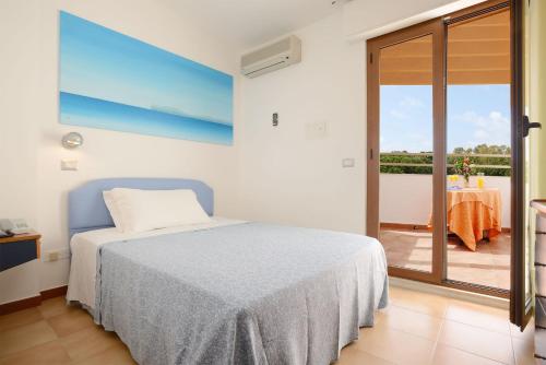 a bedroom with a bed and a balcony with a table at Hotel Oasis in Alghero