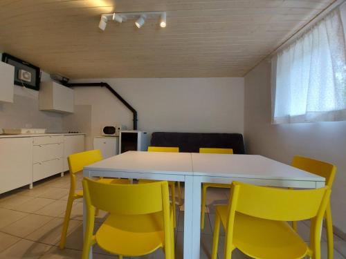 a kitchen with a white table and yellow chairs at Apartmaji Hedera in Komen