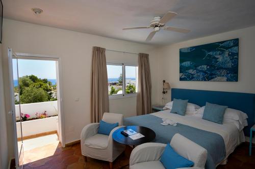 a bedroom with a bed and two chairs and a window at miKasa Agua Amarga & SPA in Agua Amarga