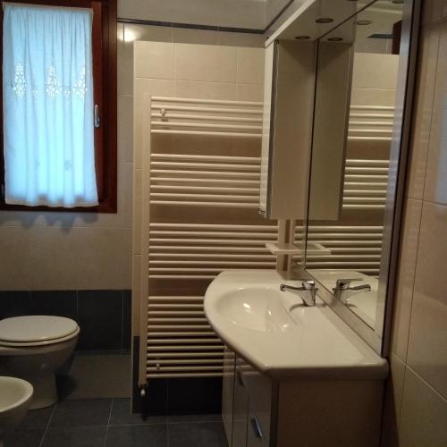 a bathroom with a sink and a toilet and a mirror at Casa Marta in Cividale del Friuli