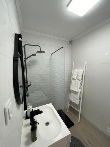 a white bathroom with a sink and a shower at Casa Paixanita - jacuzzi & terrace downtown Olhao in Olhão