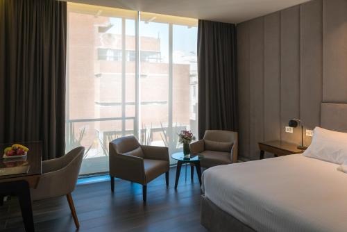 Habitación de hotel con cama, sillas y ventana en Hotel 15 de Mayo en Mar del Plata