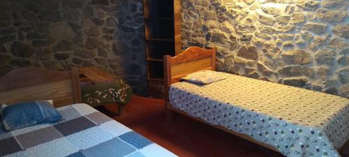 a bedroom with two beds and a stone wall at Casa De Virginia in Cabanaconde