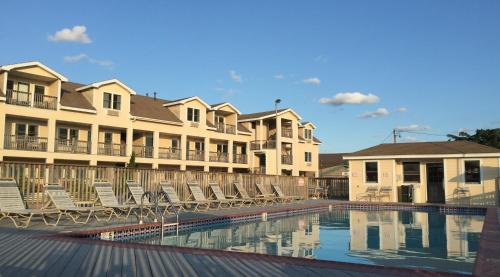 a swimming pool with chairs and some buildings at Pony Island Inn in Ocracoke
