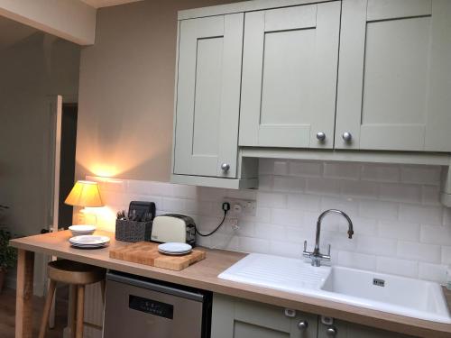 un bancone della cucina con armadi bianchi e lavandino di Nurse's Cottage a Tomintoul
