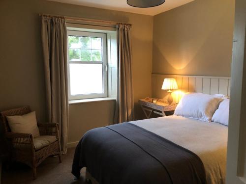 una camera da letto con un letto, una finestra e una sedia di Nurse's Cottage a Tomintoul
