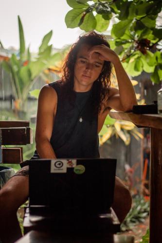 a woman sitting in front of a laptop computer at Akih Pods Hostel in Santa Teresa Beach