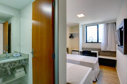 um quarto com 2 camas, um lavatório e um espelho em Go Inn Contagem - MG em Contagem