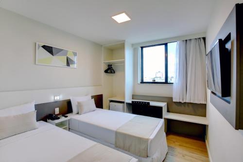 a hotel room with two beds and a window at Go Inn Contagem - MG in Contagem