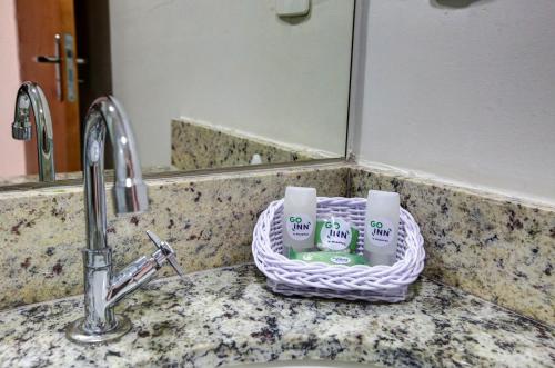 a basket of cups sitting on a bathroom sink at Go Inn Contagem - MG in Contagem