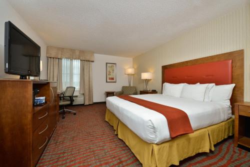 a hotel room with a large bed and a flat screen tv at Holiday Inn Express Boston-Milford by IHG in Milford