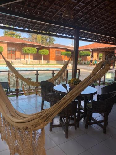 a hammock on a patio with a table and chairs at Casa chalé Gravatá in Gravatá