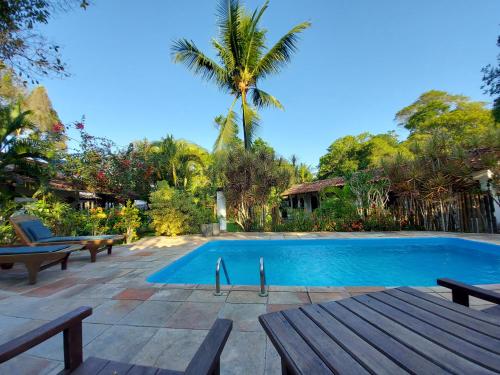 a swimming pool with benches and a palm tree at Porto do Meio in Arraial d'Ajuda