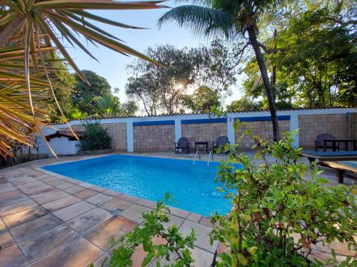 a swimming pool in a yard with a patio and trees at Porto do Meio in Arraial d'Ajuda
