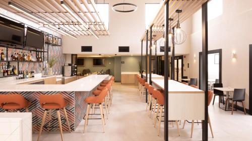 a bar in a restaurant with orange bar stools at Holiday Inn Santa Ana-Orange Co Arpt by IHG in Santa Ana