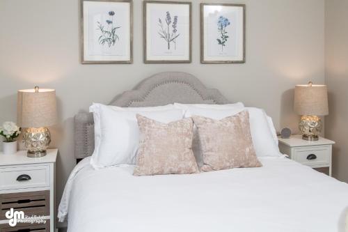 a bedroom with a white bed with three pictures on the wall at Susitna Suites in Wasilla