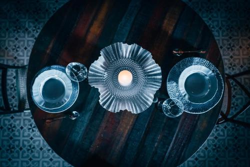a wooden table with two cups and a candle on it at LA PIANTA - Uma experiência na Villa de Monte Verde in Monte Verde