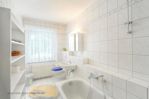 a white bathroom with a tub and a sink at Wolf, Barbara, FW 6 in Zingst