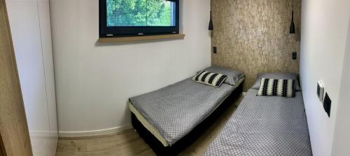 a room with two beds and a tv on a wall at Chata Thermal House in Kaluža