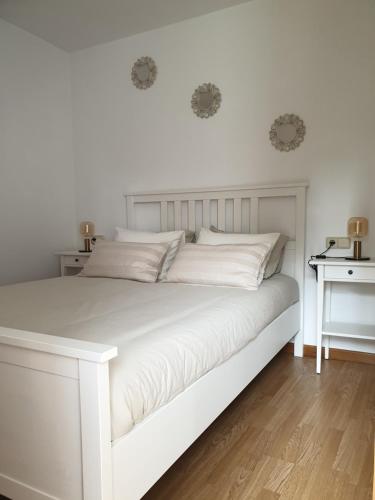 Cama blanca con sábanas y almohadas blancas en Villa Rosa, en Silleda