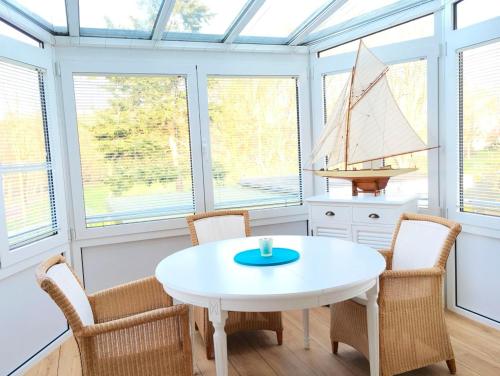 een eetkamer met een witte tafel en stoelen en ramen bij Seepark - Sonnendeck in Grömitz