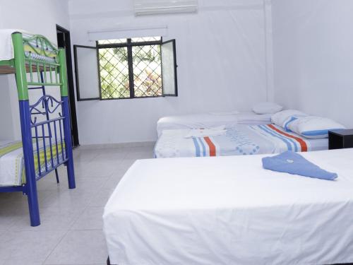 a room with three beds and a window at Villa Palmeras Hotel Campestre in Espinal