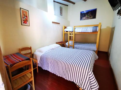 Habitación pequeña con 2 camas y 2 sillas en Hostal Apu Qhawarina en Ollantaytambo