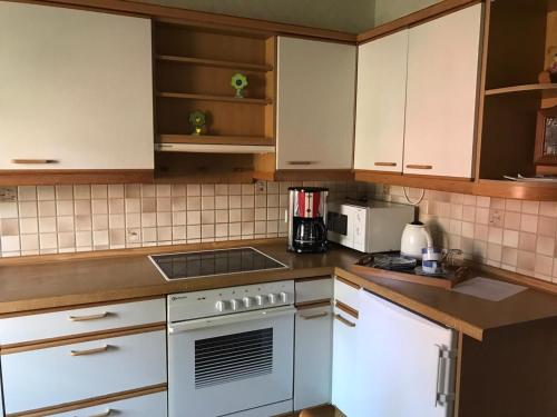 a kitchen with white cabinets and a stove top oven at Ferienhaus auf dem Hof in Wanna