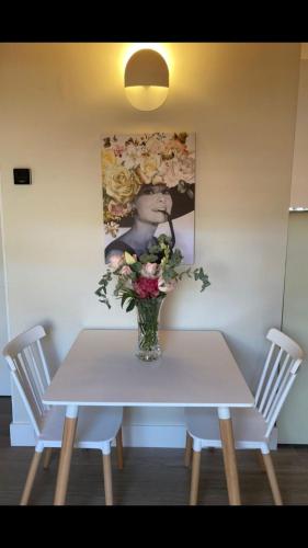 a white table with a vase of flowers on it at La Rua 25 in Castro-Urdiales