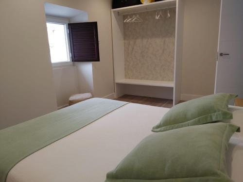 a white bed with green pillows in a bedroom at La Rua 25 in Castro-Urdiales
