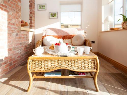 a wicker coffee table with a tea set on it at Deerholme Cottage in Malton