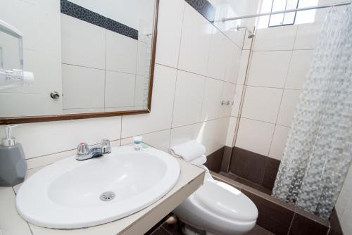 a bathroom with a sink and a toilet and a mirror at Ayenda Apart La Hacienda in Piura