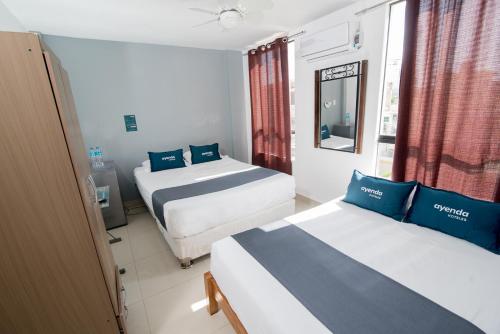a hotel room with two beds and a mirror at Ayenda Apart La Hacienda in Piura