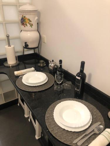 eine schwarze Theke mit zwei weißen Tellern und Weinflaschen in der Unterkunft Andrade Blue in Caniço