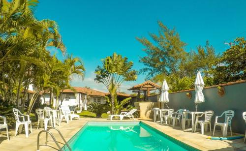 una piscina con sillas y sombrillas junto a una casa en Pousada Jardim de Búzios, en Búzios