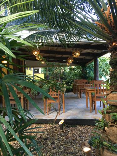 un patio con mesas y sillas bajo una pérgola de madera en Pousada Aroeira, en Barra do Sahy