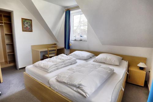 a bedroom with two beds with white sheets and a window at Am Deich 01 in Zingst