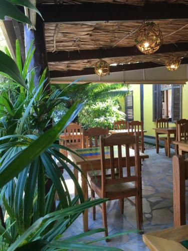 a patio with tables and chairs and a plant at Pousada Aroeira in Barra do Sahy