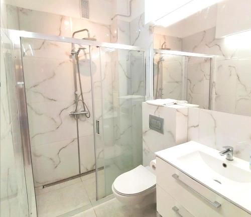 een badkamer met een douche, een toilet en een wastafel bij Metro Wilson Apartment in Warschau