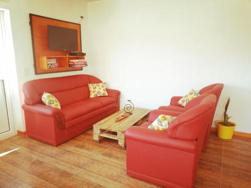 een woonkamer met 2 rode stoelen en een salontafel bij Raíces in Puerto Pirámides