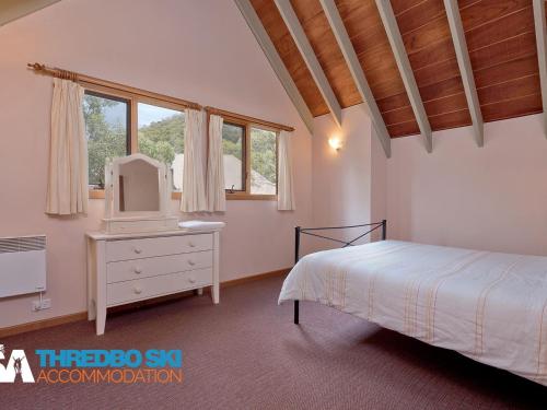 a bedroom with a bed and a dresser with a mirror at Granite Peaks 1 in Thredbo