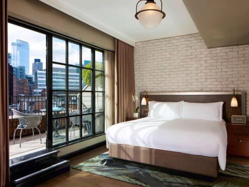 a bedroom with a large bed and a large window at Mondrian London Shoreditch in London