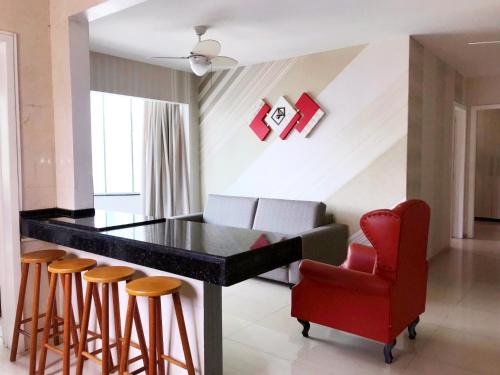 uma cozinha com uma cadeira vermelha, uma mesa e bancos em INCRÍVEL Ap a 100m do MAR com Ar e Wi-Fi no Balneário Camboriú