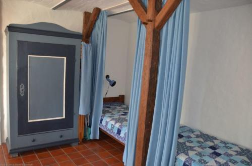 a bedroom with a bed with blue curtains and a mirror at Emes Stuuv in Oevenum