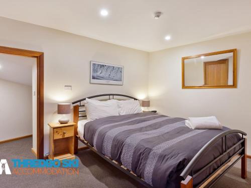 a bedroom with a large bed and a mirror at Wombiana in Thredbo