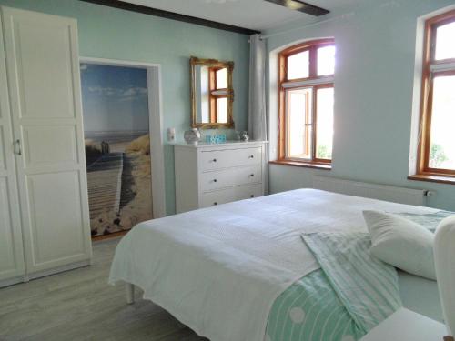 a bedroom with a bed and a dresser and windows at Komfortable Ferienwohnung "Vier Linden", ruhige dörfliche Lage, 20 min zur Küste in Kirch Mulsow