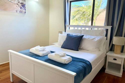 a bedroom with two towels on a bed with a window at WHISPERING PALMS in Bongaree