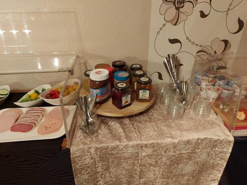 een tafel met een tafelkleed, potten en eten erop bij Hotel & Pension Haus Dewenter in Lichtenau