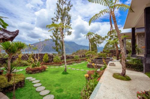 a garden with palm trees and a lawn with rocks at Break Villa Kintamani in Kintamani