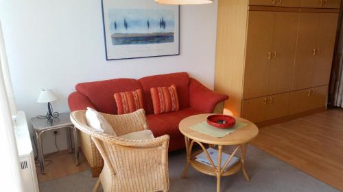 ハイリゲンハーフェンにあるBlohm, Steinwarder 37b-4-7のリビングルーム(赤いソファ、テーブル付)